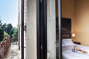 Habitación de hotel con una cama, una bandeja con productos de desayuno y vistas a un balcón con barandilla.
