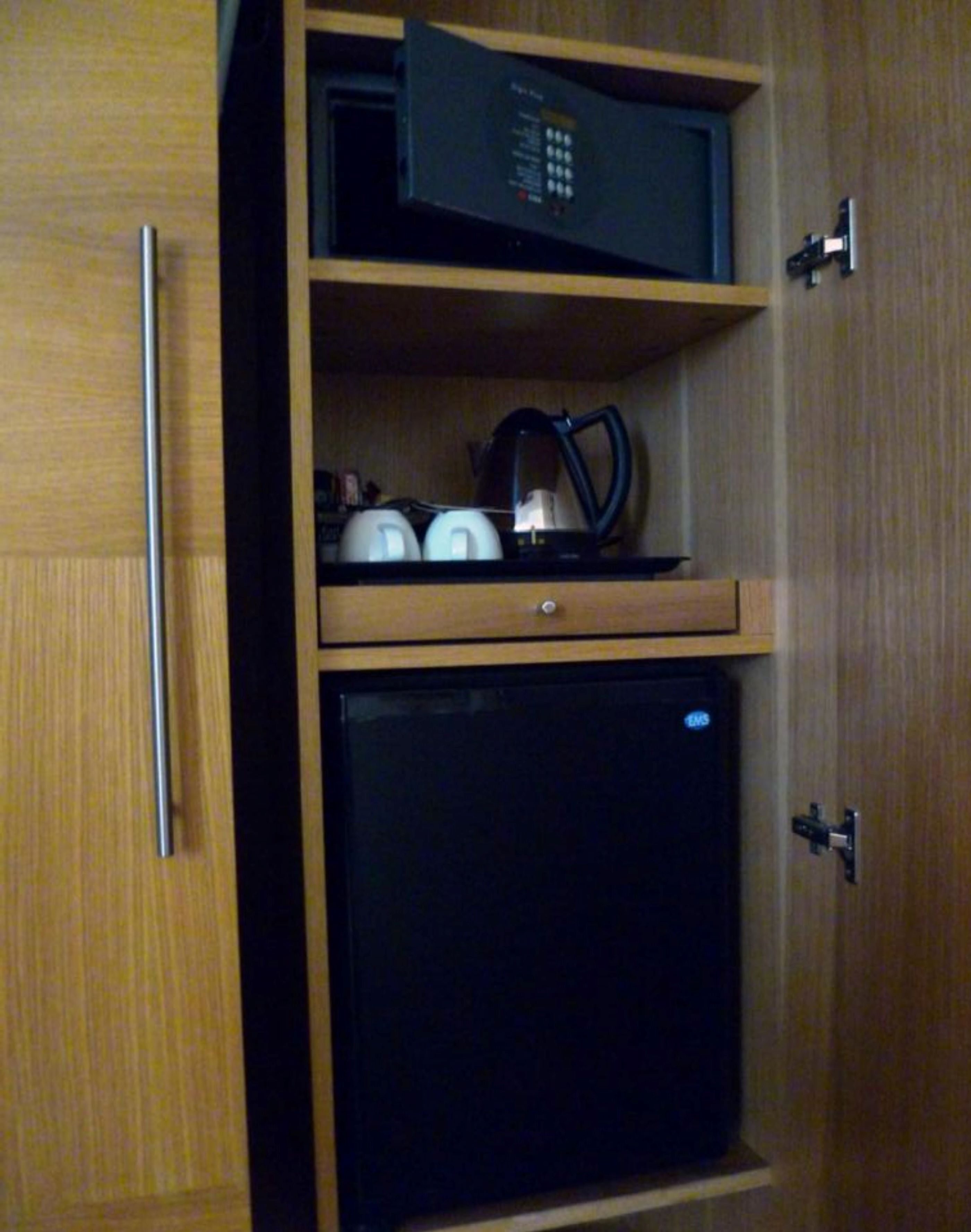 A wooden cabinet with a black refrigerator and a microwave on the top shelf.