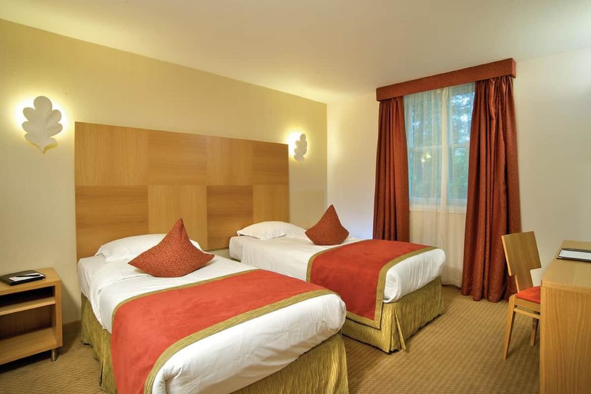 Une chambre d’hôtel avec deux lits, un bureau et une chaise.