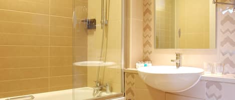 A modern bathroom with a glass-enclosed shower, a white sink, and a large mirror.