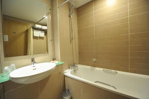 Un baño con lavamanos, espejo y bañera.