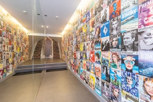 Un pasillo con una pared decorada con diversas portadas de revistas y periódicos.