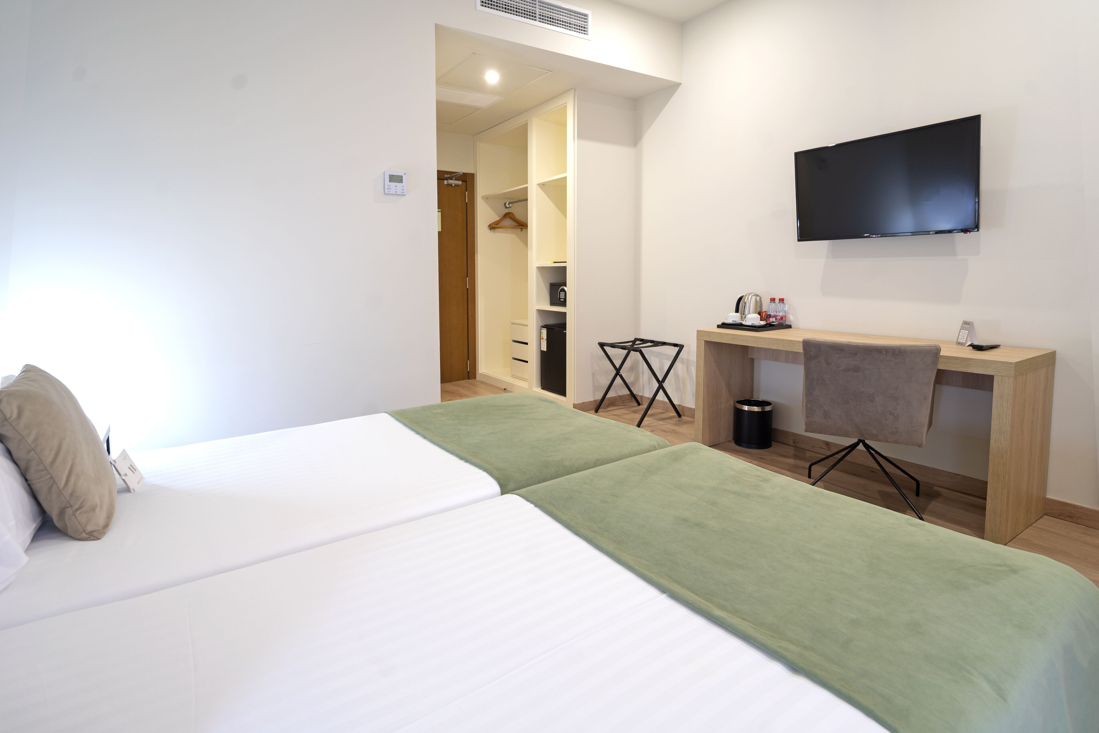 A hotel room with a bed, a desk, a TV, and a walk-in closet.