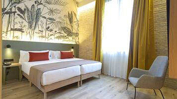 A hotel room with a large bed, a chair, a desk, and a mural on the wall.