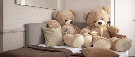 A bed with two large teddy bears, a pillow, and a blanket.
