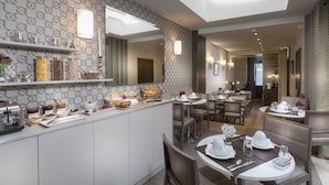 Un comedor de hotel moderno con barra de desayuno, armarios blancos y un revestimiento de pared estampado.