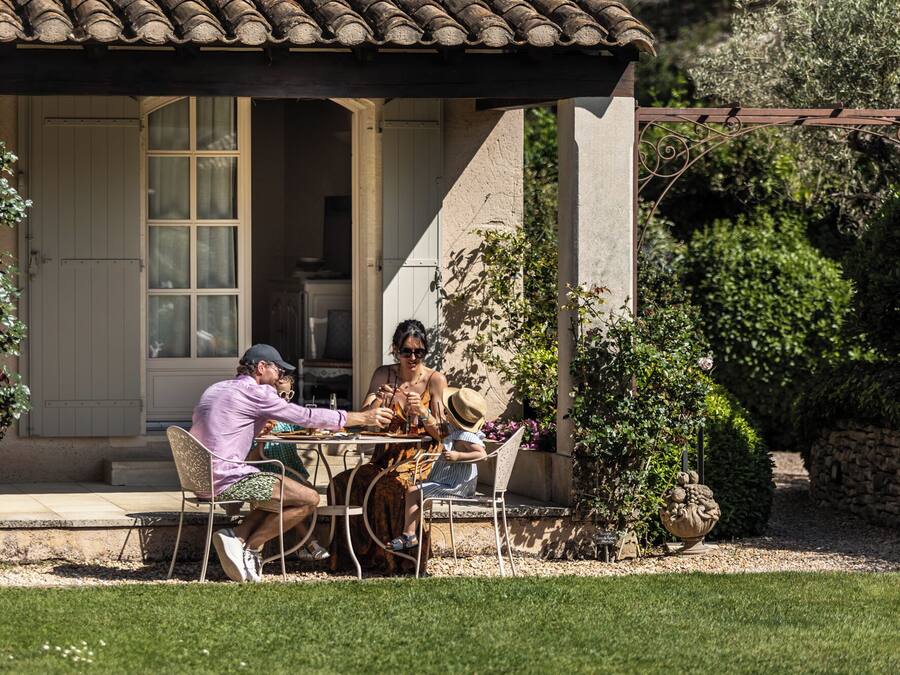A patio with a table and chairs, a stone wall, and a garden with various plants.