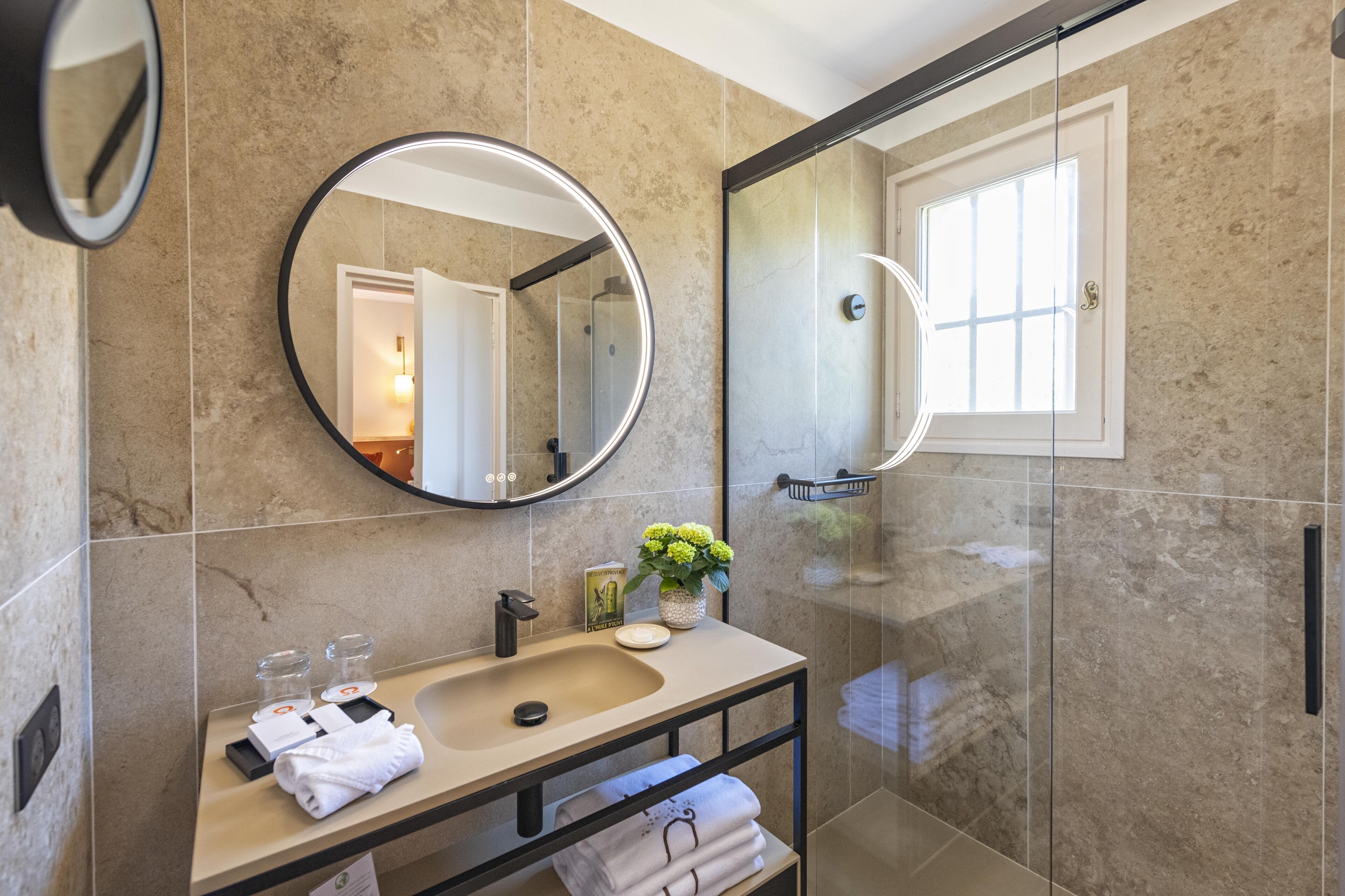 Een moderne badkamer met een ronde spiegel, een wastafel en een douchecabine van glas.