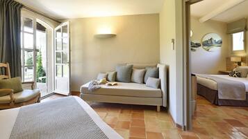 A hotel room with a bed, a sofa, a dining table, and a view of the outdoors.