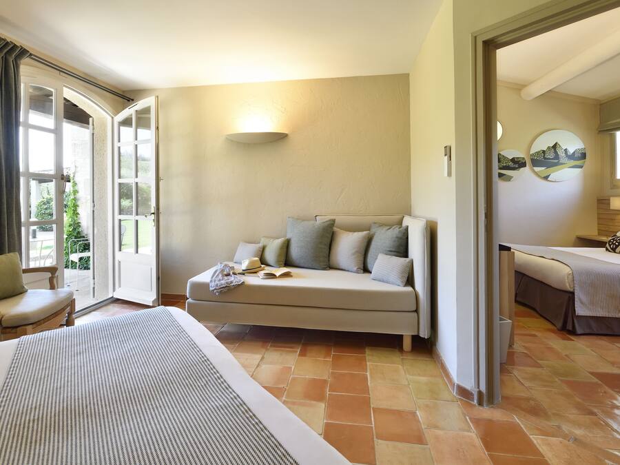 Habitación de hotel con cama, sofá, mesa de comedor y vistas al exterior.