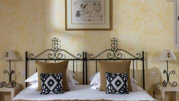 A neatly made bed with patterned pillows, a framed artwork above, and two bedside tables with lamps.