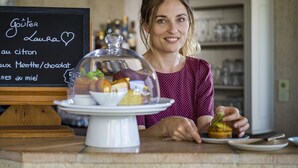 Eine Frau steht an einem Tresen, hinter ihr eine Speisekarte.