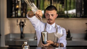 Ein Barkeeper gießt einen Drink in einen Shaker.