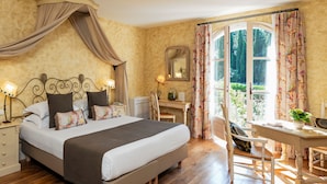 Ein Schlafzimmer mit einem großen Bett, einem Schreibtisch und Blick auf Grünflächen.