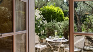 Eine Terrasse im Freien mit einem runden Tisch, zwei Stühlen und einem Blumentopf.
