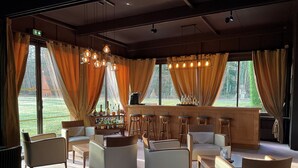 Ein stilvoller Lounge-Bereich mit Sitzgelegenheiten, einer Bar und großen Fenstern mit Vorhängen.