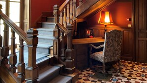 Eine prächtige Treppe mit Schachbrettmuster, einem Holengeländer und einer Lampe auf einem Tisch.