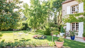 A well-maintained garden with a patio, seating area, and potted plants. - Le Petit Manoir Des Bruyeres (Villefargeau)