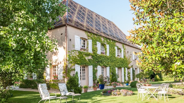 A building with a garden, outdoor seating, and a tiled roof. - Le Petit Manoir Des Bruyeres (Villefargeau)