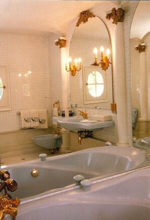 A bathroom with two sinks, a bathtub, and a large mirror. - Le Petit Manoir Des Bruyeres (Villefargeau)