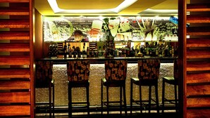 A bar area with wooden paneling, a bar counter, and three patterned bar stools. - Hôtel Les Saisons (Casablanca)