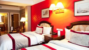 A hotel room with two beds, a wooden headboard, a nightstand, a lamp, and a framed picture on the wall. - Hôtel Les Saisons (Casablanca)