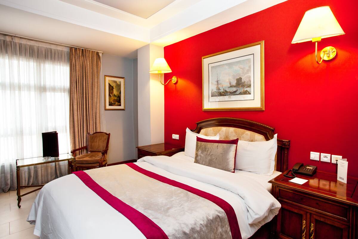 Habitació d'hotel amb un llit, una cadira, un escriptori i una làmpada.