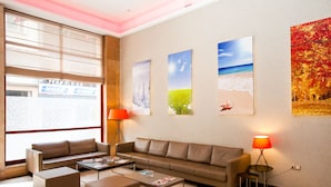 A modern living room with a sofa, ottomans, a coffee table, and two floor lamps. - Hôtel Les Saisons (Casablanca)