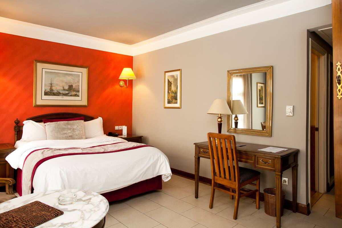 Habitació d'hotel amb llit, escriptori, cadira i mirall.