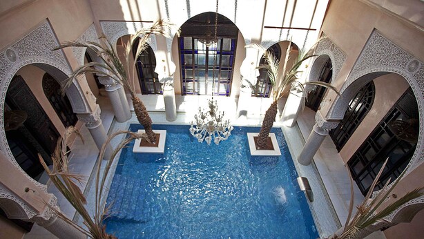 Una piscina interior con arcos ornamentales y una araña.