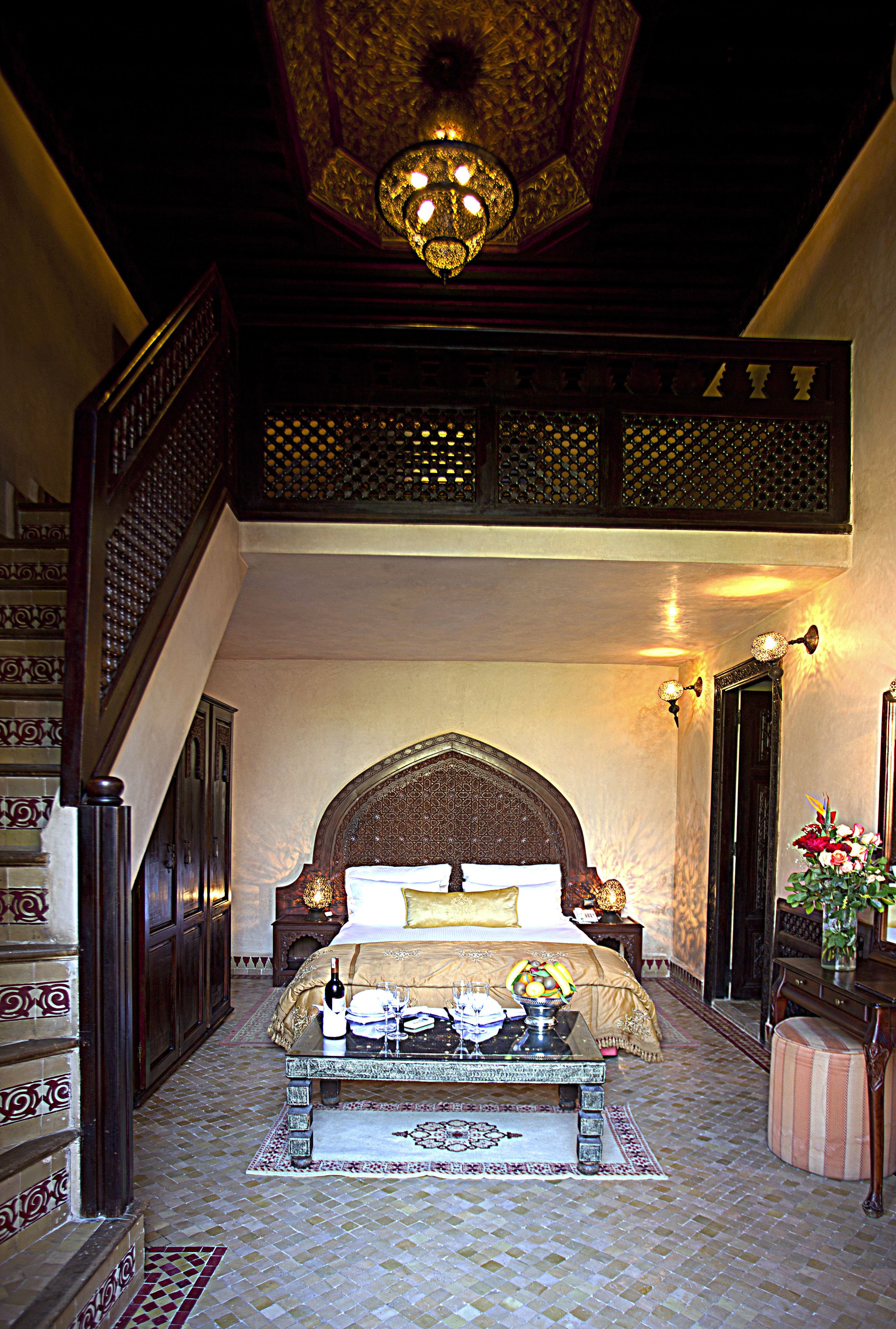 Ein Schlafzimmer mit einem großen Bett, einer Holztreppe, einer Chandelier und einer Wandverkleidung.