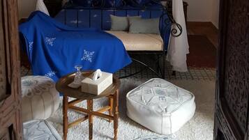 A room with a bed under a canopy, a small table with a tissue box, and decorative ottomans.