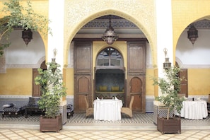 Una entrada ornamentada con suelo de baldosas, una puerta de madera y un banco en el exterior.