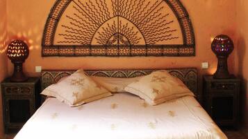 A bedroom with a bed, two nightstands, a decorative wall piece, and a small table with a magazine.