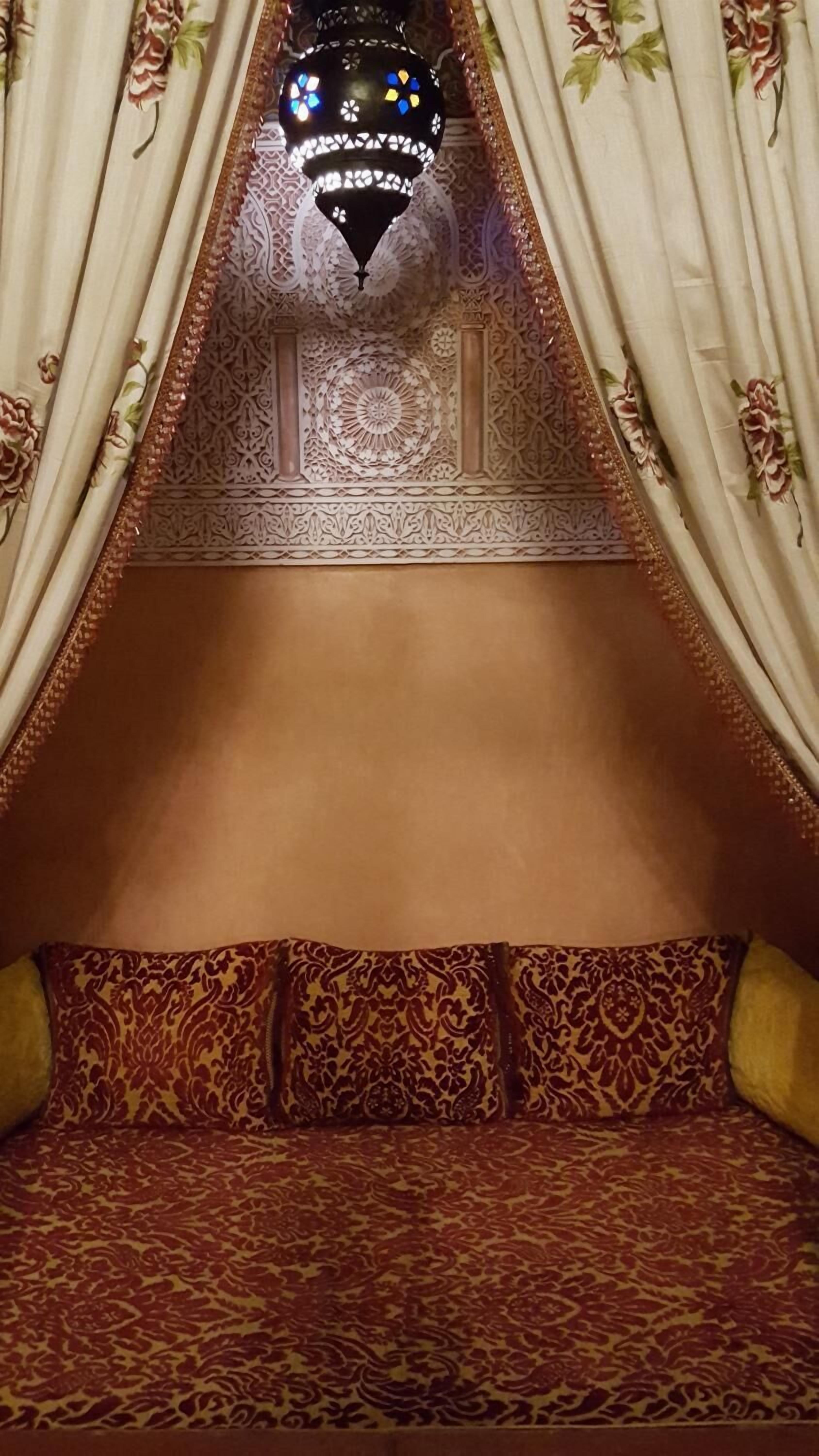 A room with a canopy bed, ornate ceiling, and patterned curtains.