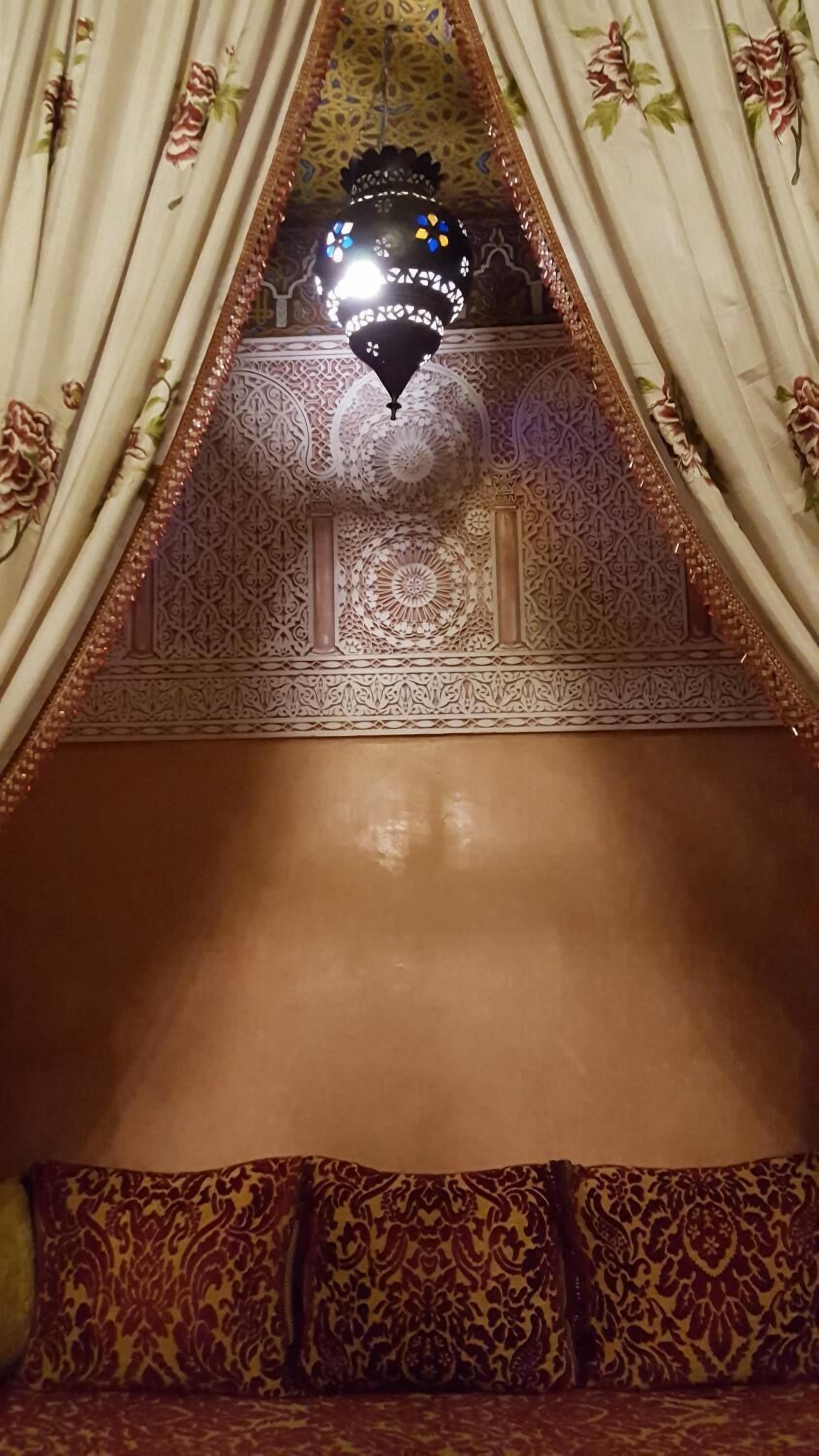 Una habitación con techo estampado, lámpara colgante y cama con ropa de cama estampada.