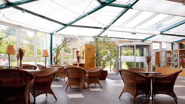 A covered outdoor seating area with wicker furniture and potted plants.