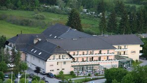 A multi-story hotel with a central courtyard, surrounded by greenery and trees.