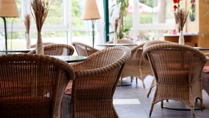 Wicker chairs and tables in a bright, naturally lit indoor space with large windows.