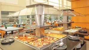 A buffet setup with multiple food stations and a large window in the background.