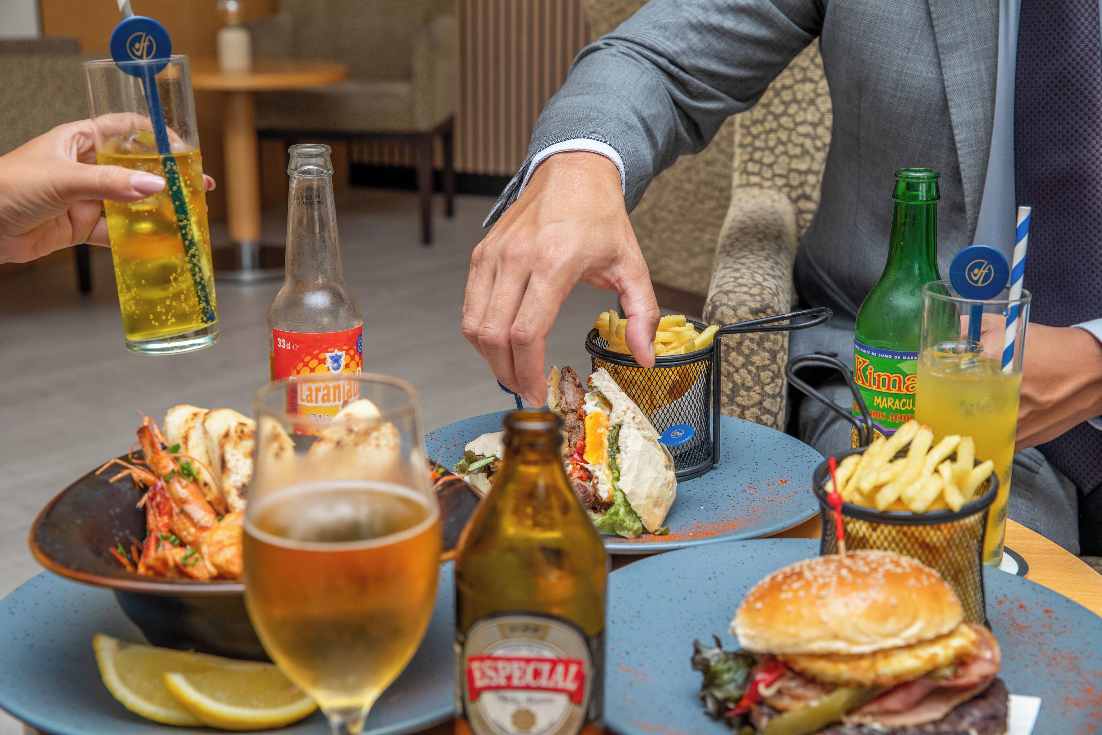 A dining table with various food items, drinks, and a bottle of beer.