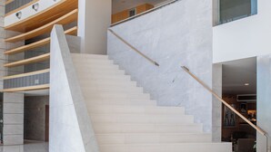 A modern interior with a staircase, wooden beams, and a marble floor.