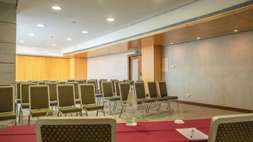 A conference room with rows of chairs, a table with a red tablecloth, a water bottle, and a glass.