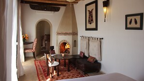 A cozy room with a fireplace, a dining table, and a sofa. - Riad Clémentine (Marrakech)
