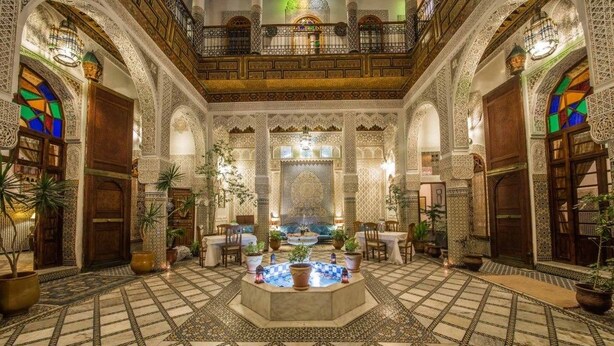 A spacious courtyard with a central fountain, surrounded by ornate arches and potted plants. - Riad Sara (Fes)