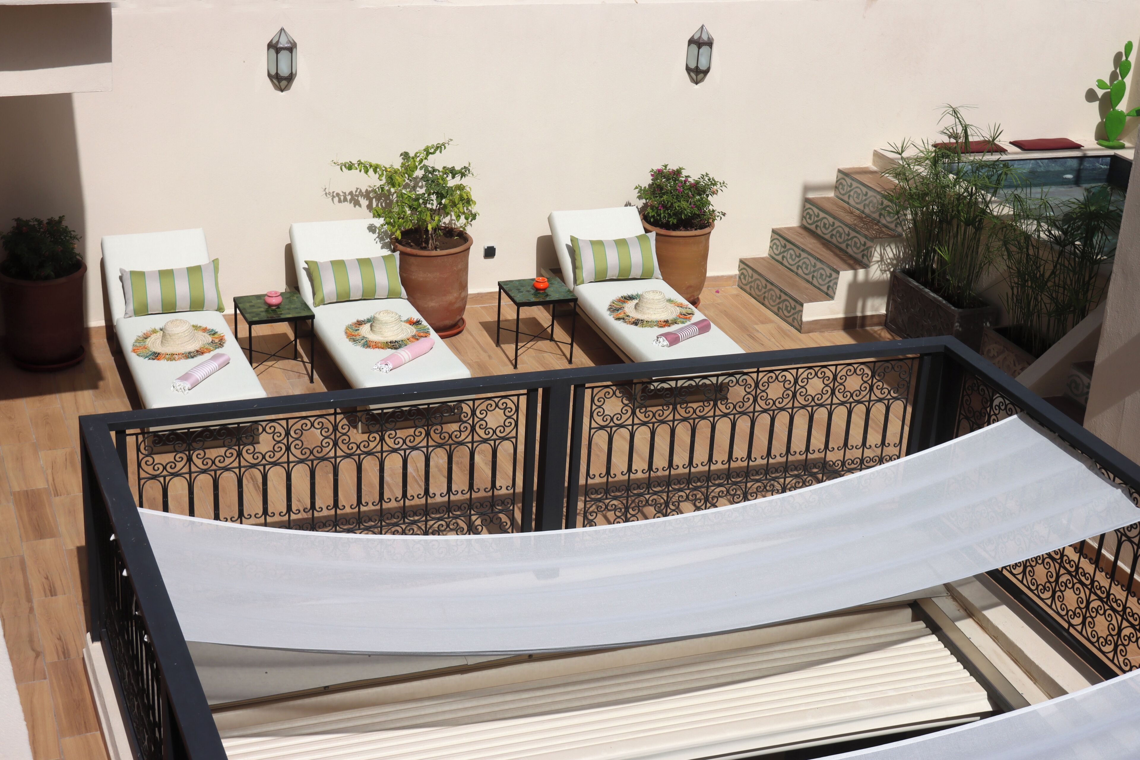 A balcony with two lounge chairs, potted plants, a small table, and a staircase.
