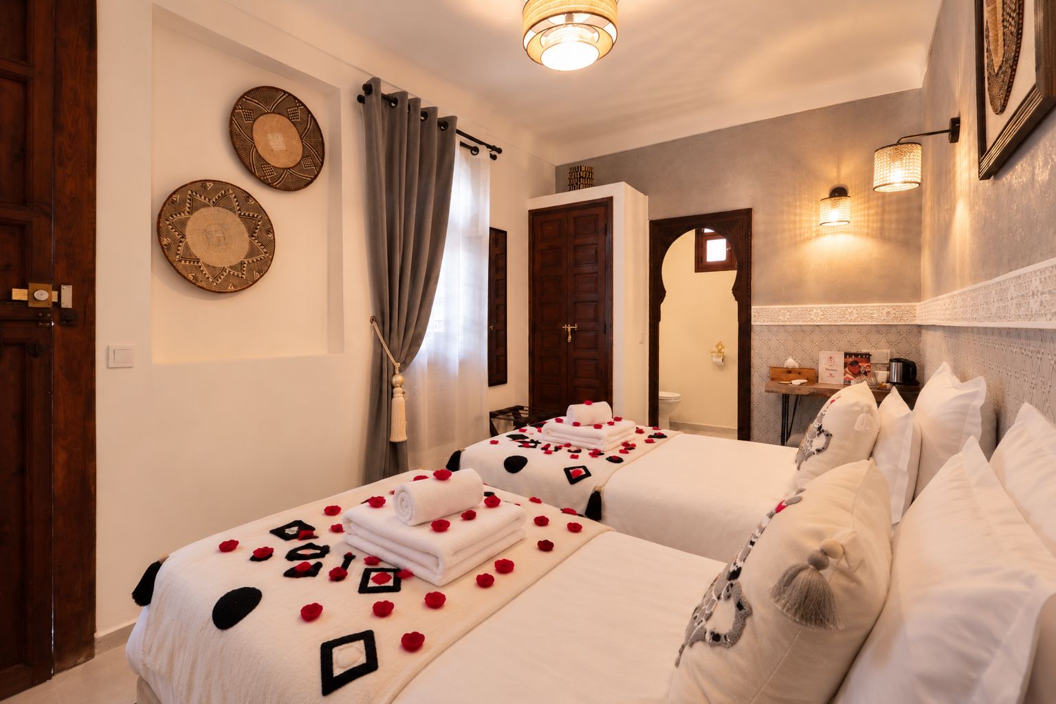 Una camera d'albergo con due letti, un bagno e un piccolo angolo salotto.