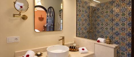 A bathroom with a round mirror, a sink, and a shower area.