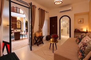 A well-lit living room with a sofa, a coffee table, and a dining area with a table and chairs. -  Riad Laora et SPA (Marrakech)