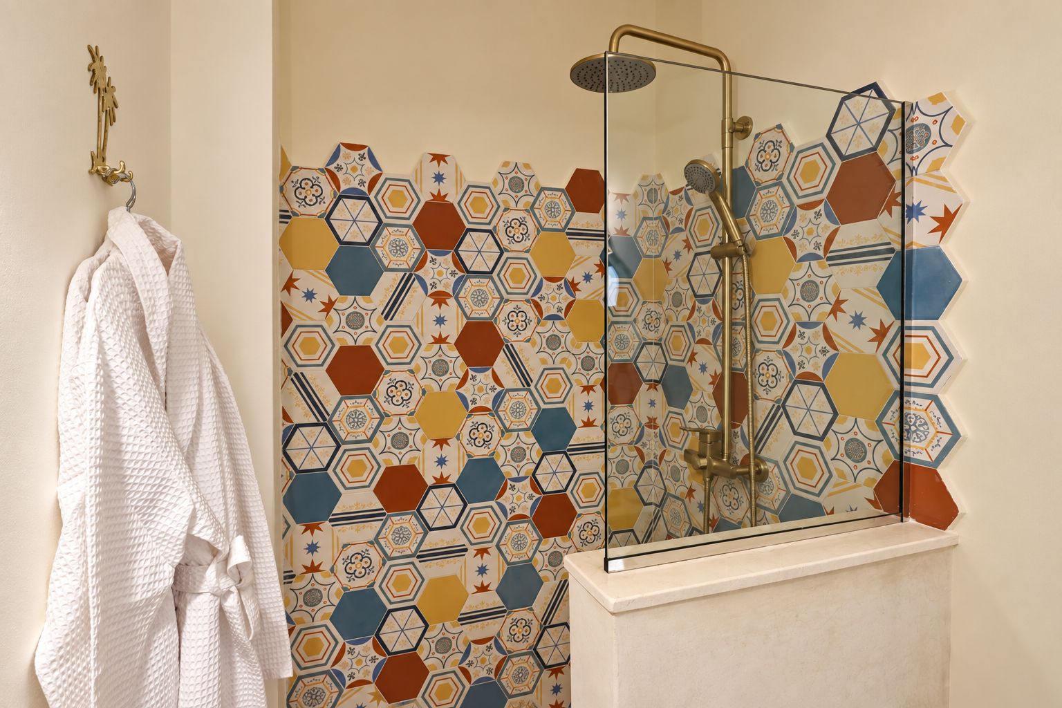 A bathroom with a shower, a towel rack, and a wall with a geometric tile pattern.